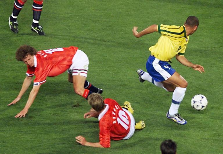 Brazilian forward Ronaldo (R) passes by Norwegian defender Dan Eggen (L) and midfielder Kjetil Rekdal (#10) as they fall down 23 June at the Stade Velodrome in Marseille, south of France, during the 1998 Soccer World Cup Group A first round match between Brazil and Norway.
(ELECTRONIC IMAGE) AFP PHOTO   GEORGES GOBET (Photo by GEORGES GOBET / AFP) (Photo by GEORGES GOBET/AFP via Getty Images)          
